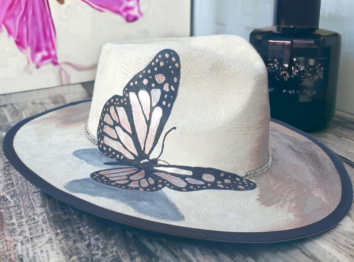 white hat with handmade butterfly painted with metalic colours