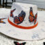 Orange butterflies handpainted on a white hat with silver details