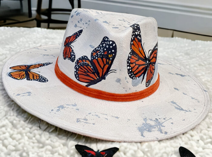 Orange butterflies handpainted on a white hat with silver details